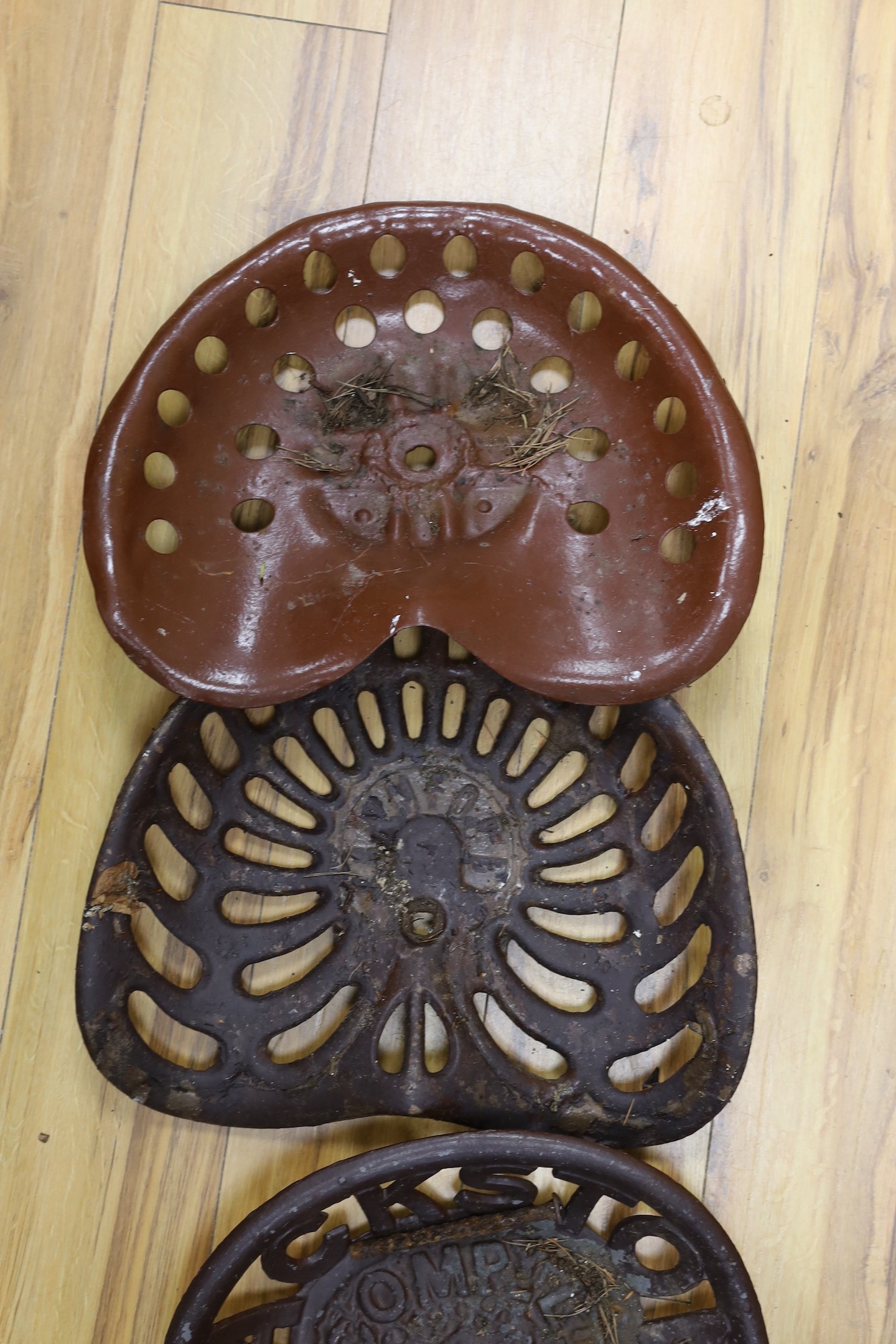 Four assorted cast iron and enamelled tractor seats